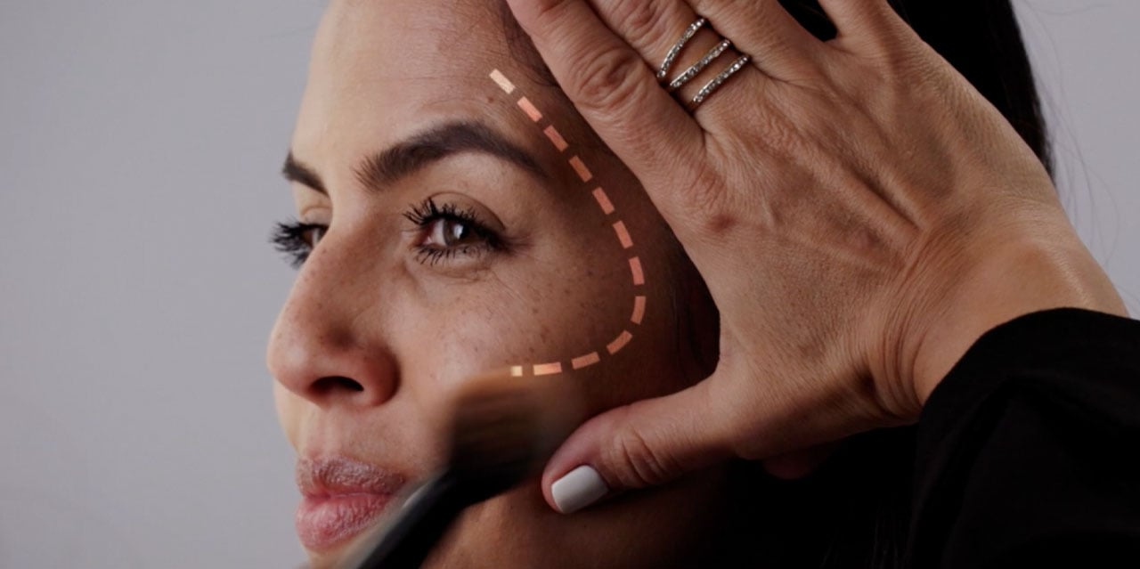 Makeup artist applying bronzer to model using the L technique for a lifted look